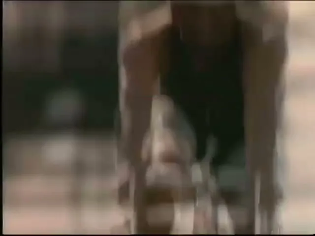 Bo Jackson, a male athlete, wears a white helmet and black tank top while cycling outdoors on a sunny day.