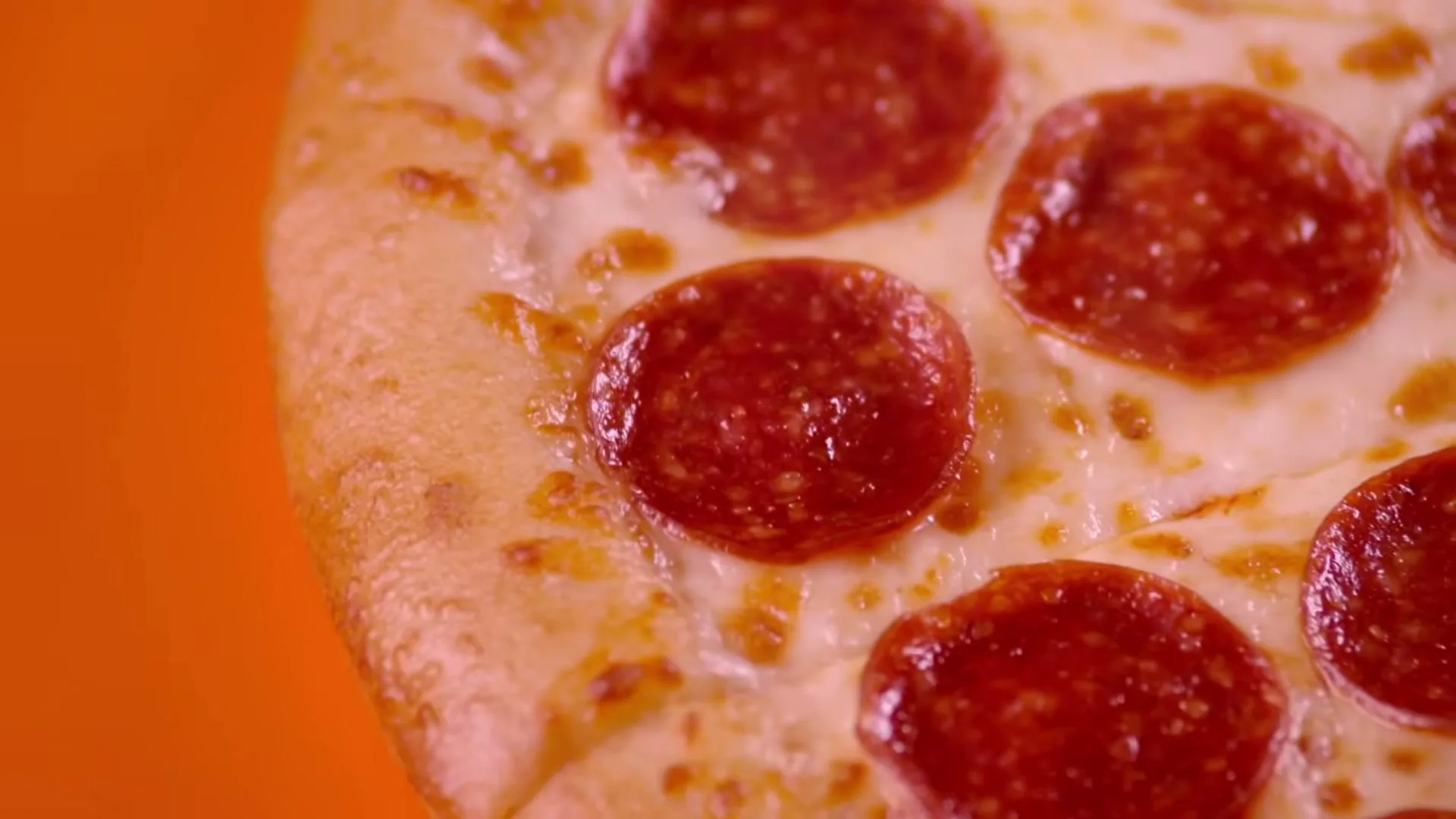 A close-up shot of a pepperoni pizza with melted cheese on an orange background, with the text "Hot-N-Ready" overlaid.