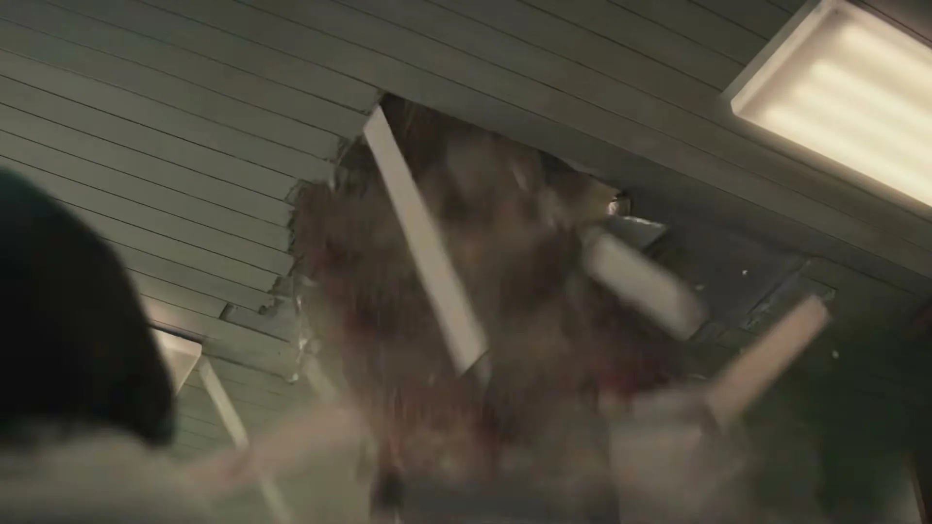 A person looks up as a ceiling panel collapses, revealing a shower of colorful Skittles candies falling into the room.