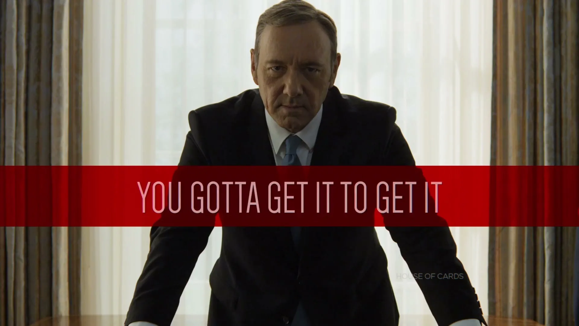 Kevin Spacey as Frank Underwood, a male in his 50s, stands behind a desk, looking directly at the camera with a serious expression in an office.