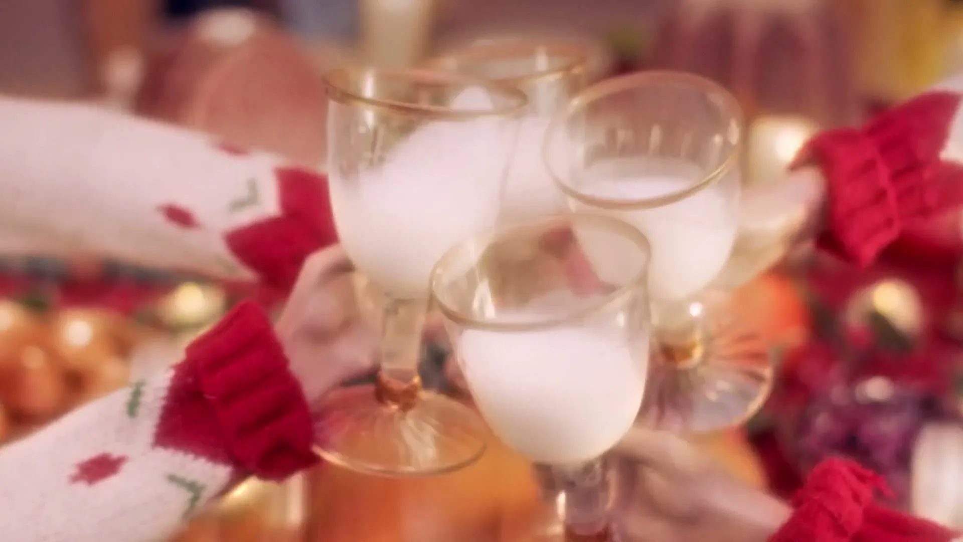 A group of people in festive sweaters toast with glasses of milk, then a raw turkey with sunglasses and a bow tie appears on a holiday dinner table.