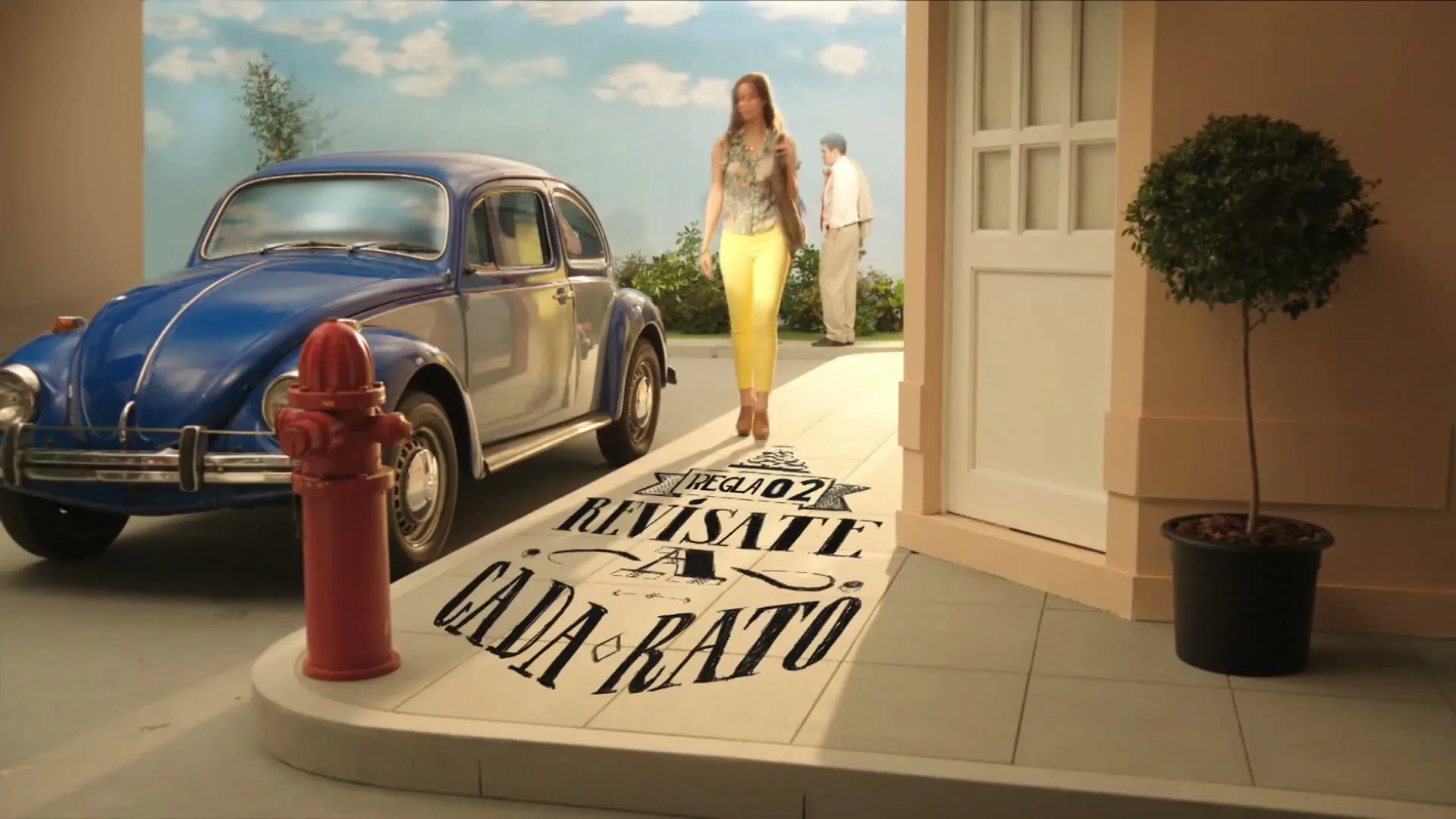 A woman in yellow pants and a patterned top walks on a sidewalk with a blue car and a red fire hydrant in the background, with text appearing on the ground.