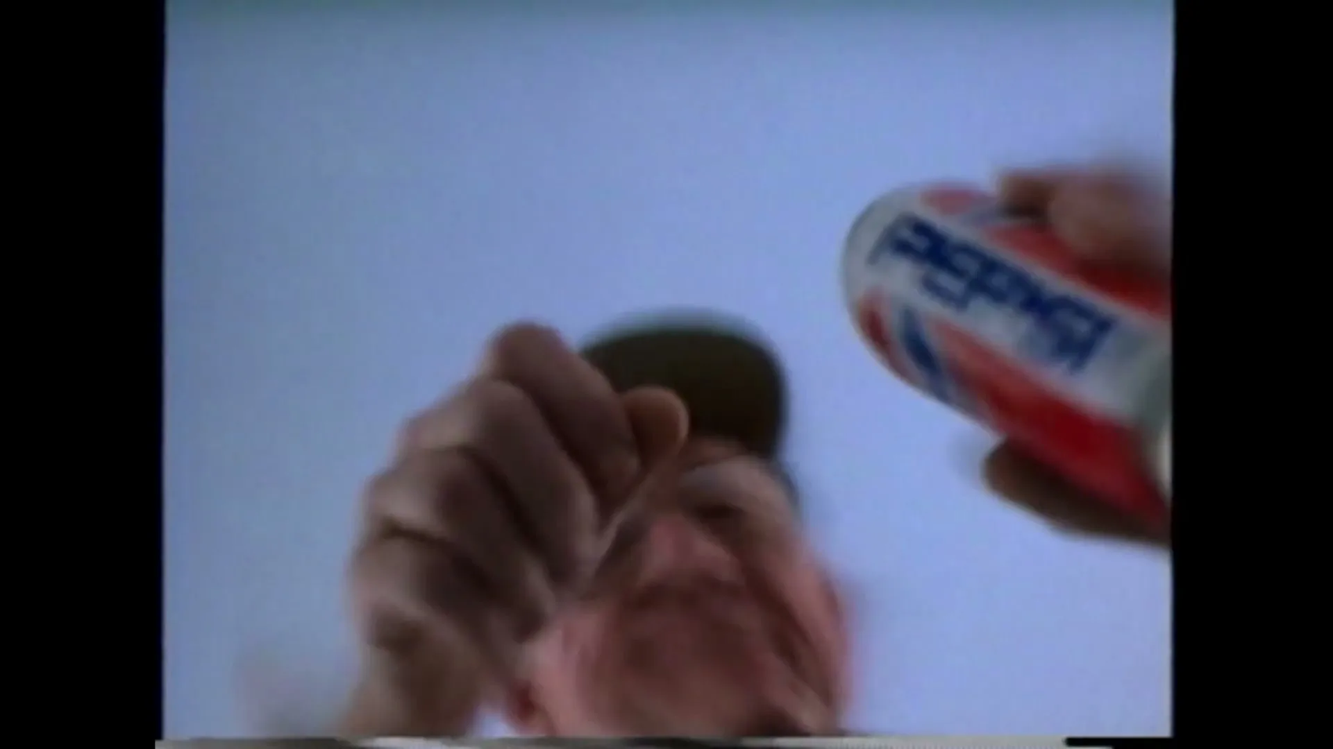 A man's face is seen from below as he tries to grab a Pepsi can, which is then pulled away from him.