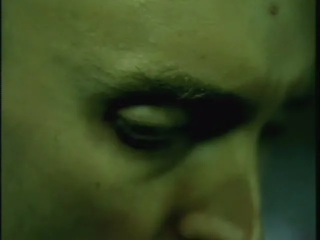 A man's eye is shown in extreme closeup, looking down, with a green tint over the image.