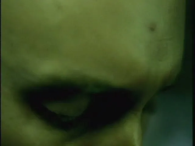 A person's face, with dark shadows around their eyes, is shown in a tight closeup as they look down.