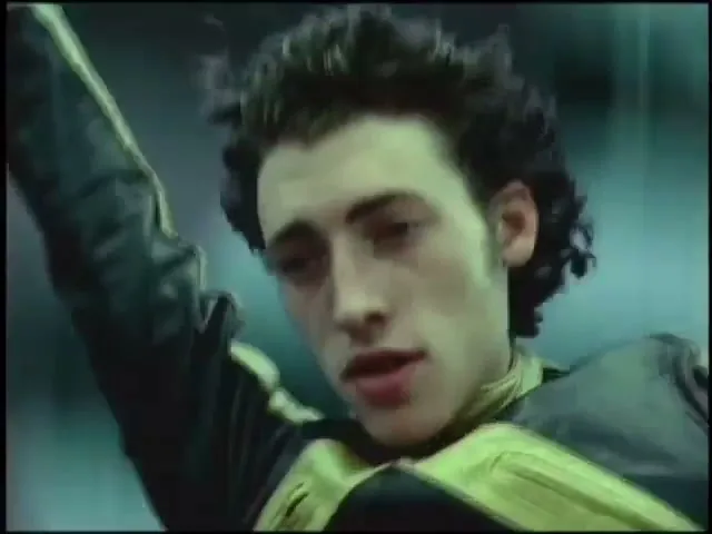 A young man in a futuristic suit jumps from a skyscraper, falling through the air with a city skyline in the background.