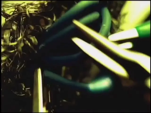 A close-up shot shows a pair of scissors cutting through a tangled mess of wires and cables, with a dark, chaotic background.
