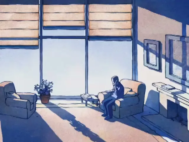 A man in a blue suit sits down in an armchair in a brightly lit living room with large windows, talking on a landline phone.