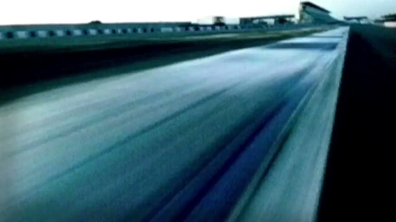 A low-angle shot captures a race track at dusk, with the ground blurring from motion, suggesting high speed.