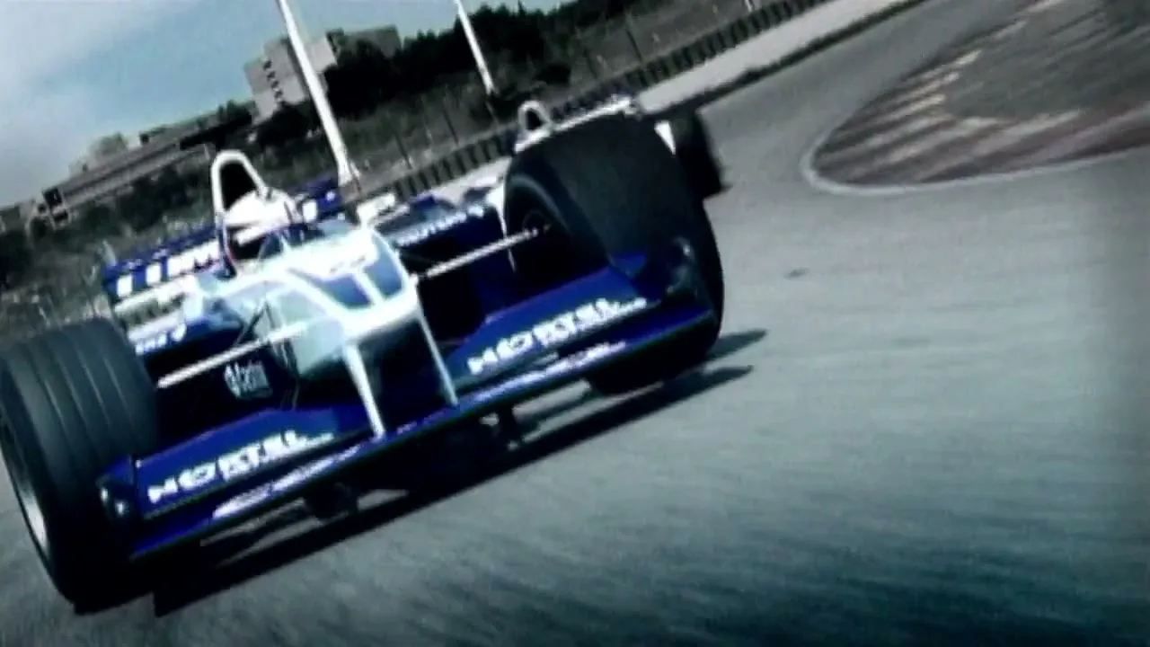Two blue and white Formula 1 race cars speed around a track on a sunny day.