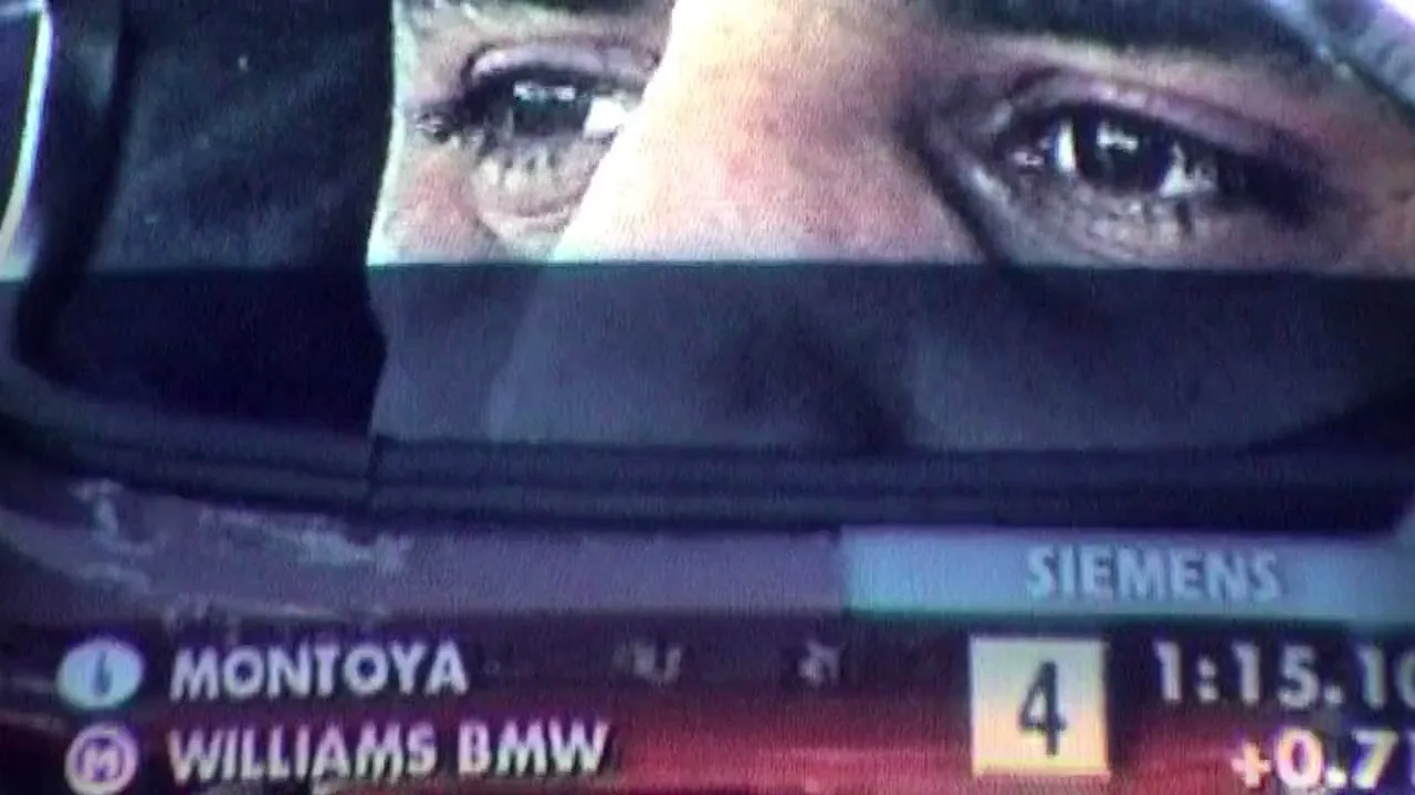 A man's eyes are visible above a racing helmet, with racing statistics and sponsor logos displayed below, in a dark setting.