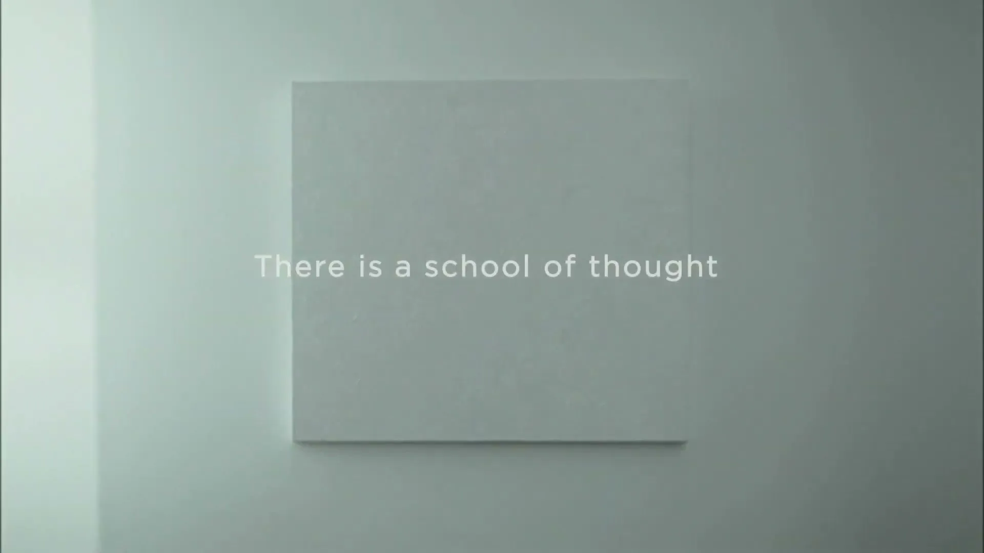 White text appears on a plain white wall, stating "There is a school of thought" in a clean, minimalist setting.