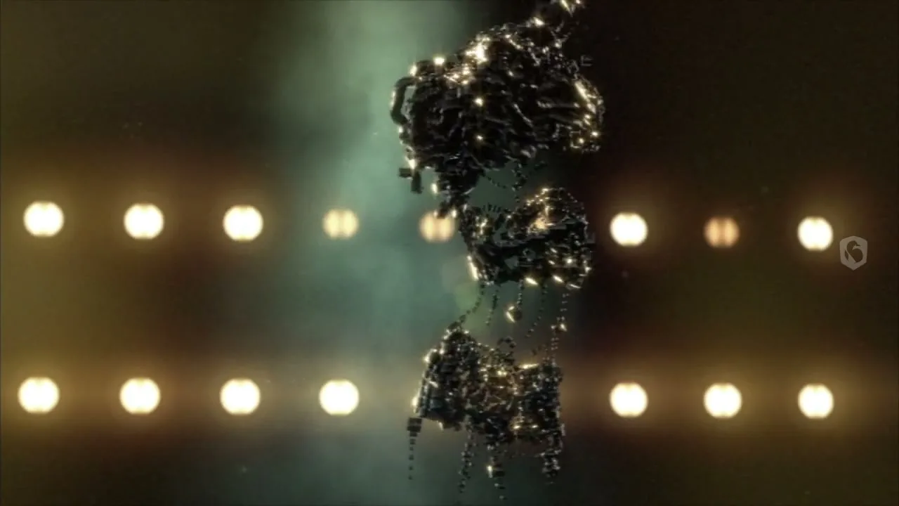 A dark, abstract, organic-looking shape, made of many small, shiny particles, floats and pulsates in the center of the frame, against a blurry background of two rows of bright, circular lights.