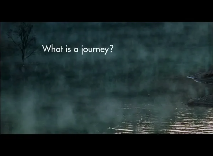A wide shot of a misty lake at dawn, with a bare tree partially submerged in the water and the text "What is a journey?" overlaid.