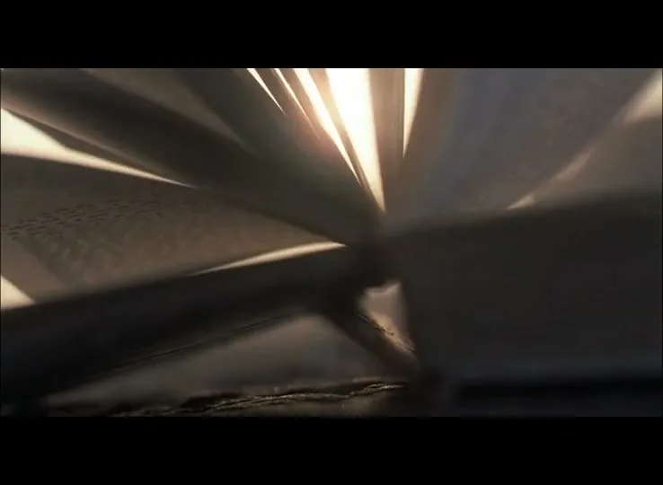 A book's pages rapidly turn, illuminated by a bright light shining through them, creating a dramatic effect.