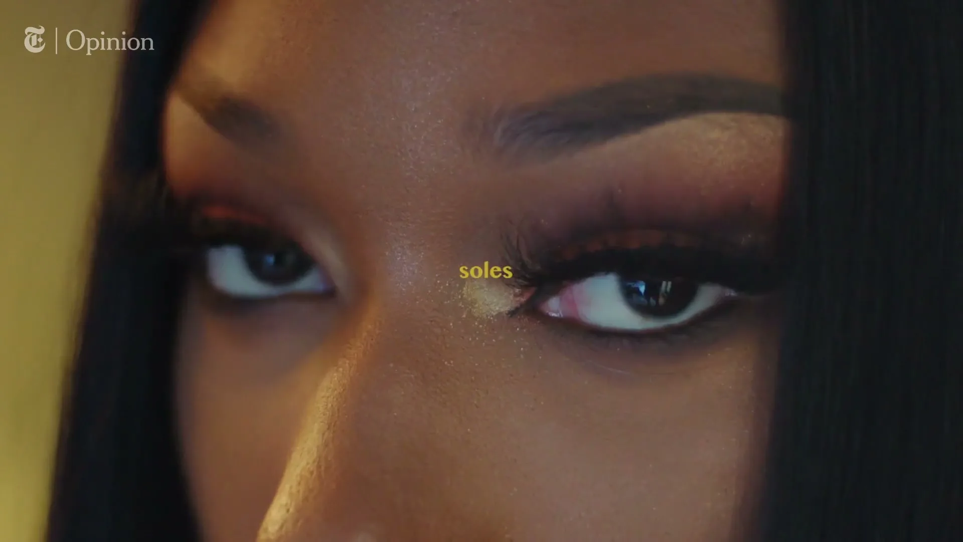 A woman with dramatic eye makeup opens her eyes, looking directly at the camera, with text appearing on screen.