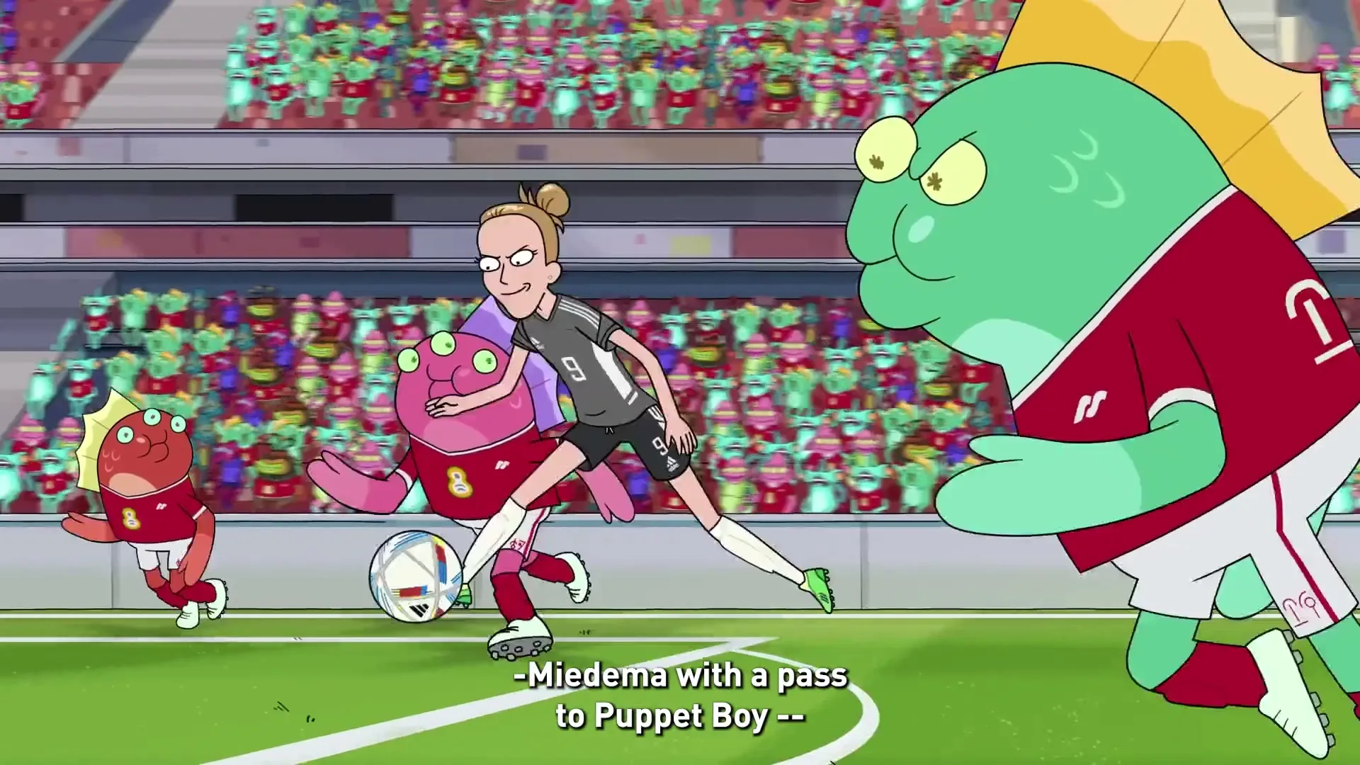 Vivianne Miedema, a female soccer player, passes the ball to a pink alien who falls, while a green alien watches on a soccer field.