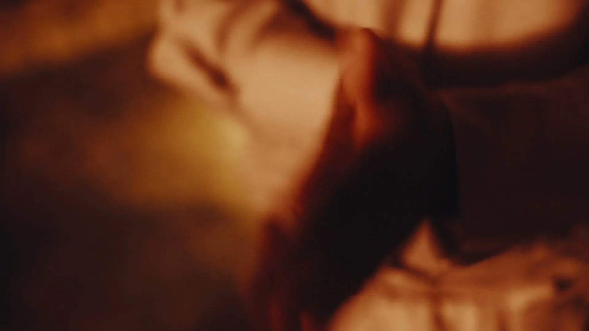 A blurry shot of a person's hands moving quickly, illuminated by a warm, orange light in an interior setting.