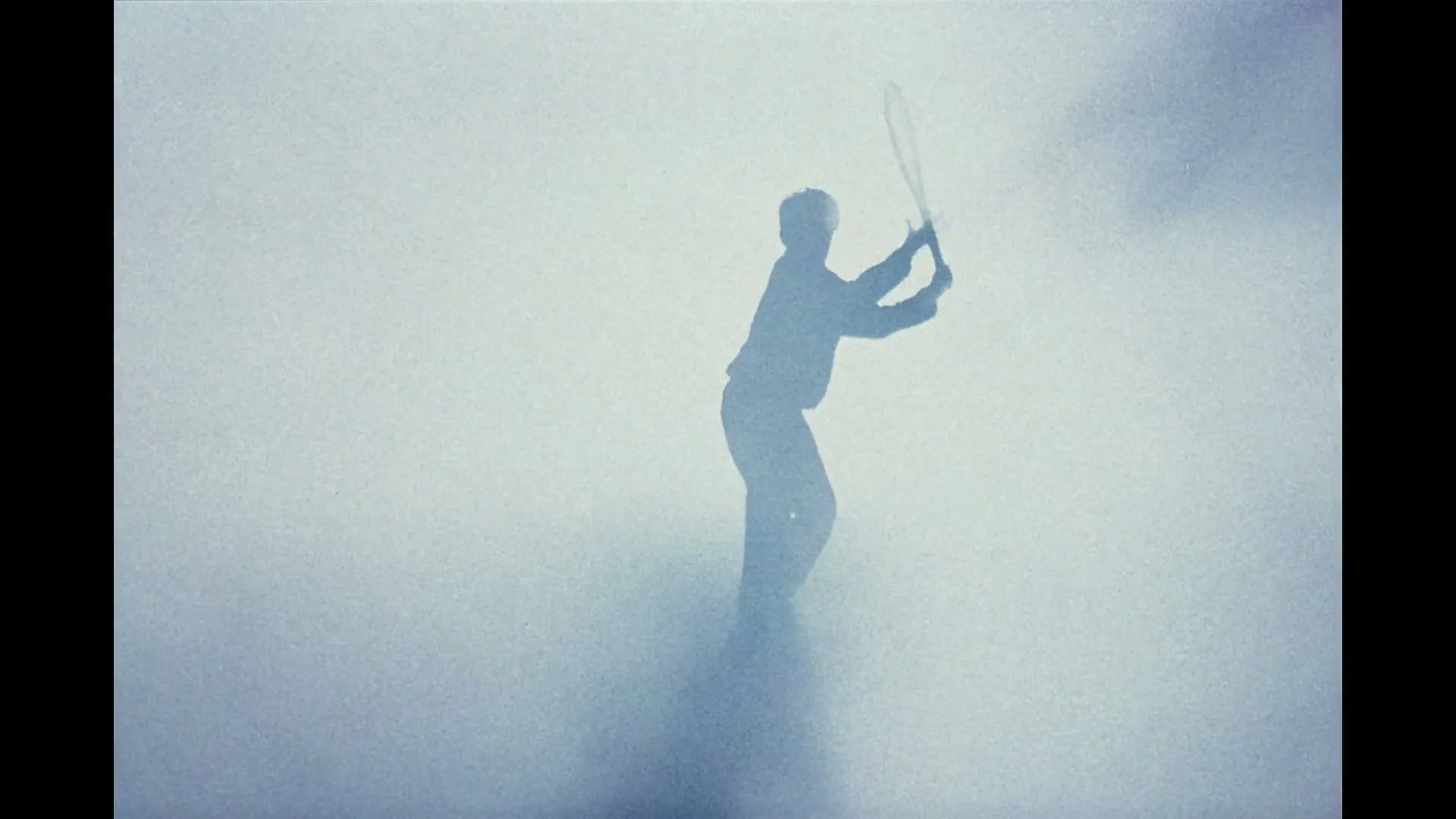 A silhouetted figure, possibly a male, is seen through a hazy, smoky environment, swinging a tennis racket.