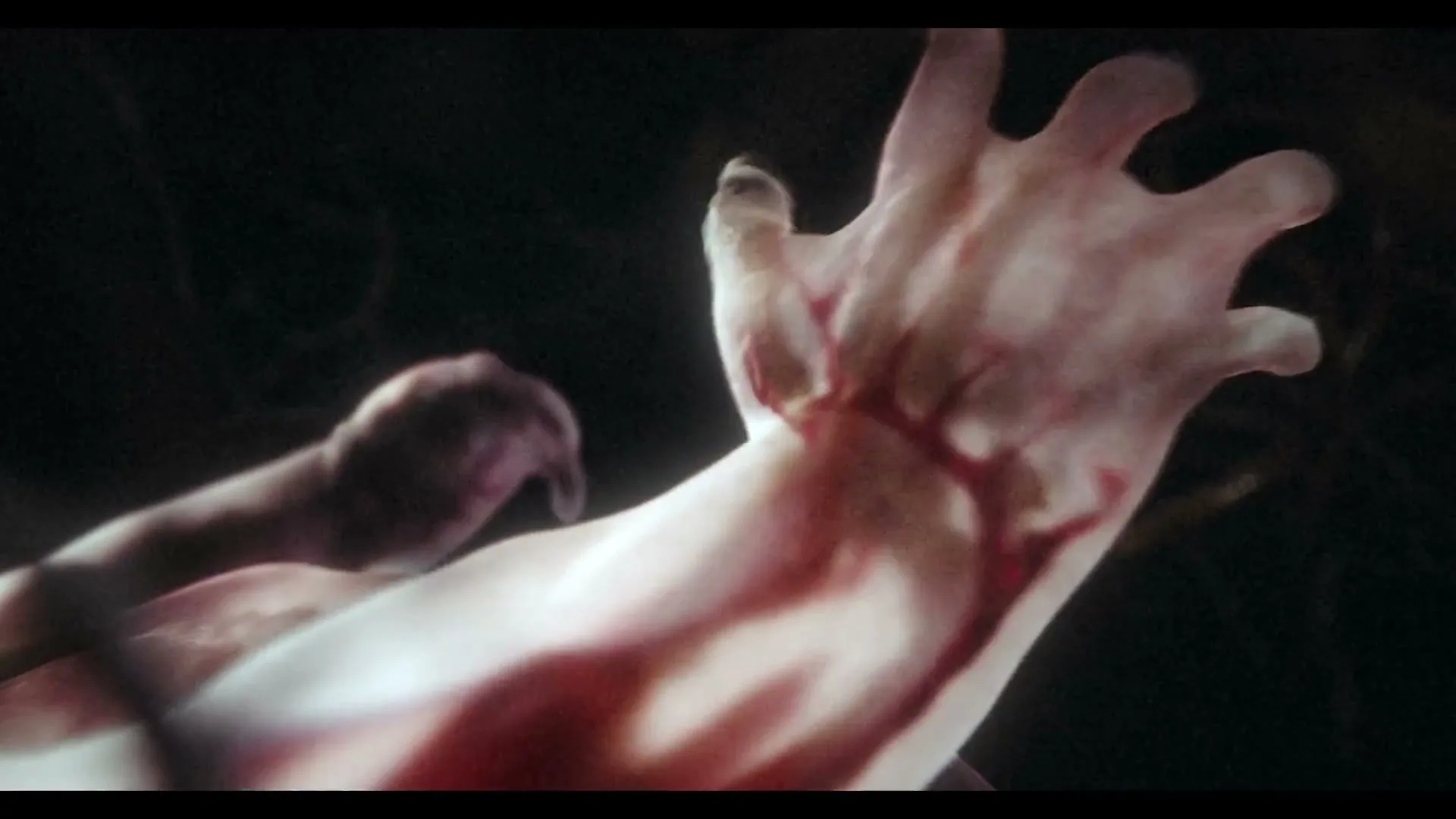 A close-up shot of a human arm covered in blood, reaching upwards in a dark, ominous setting.