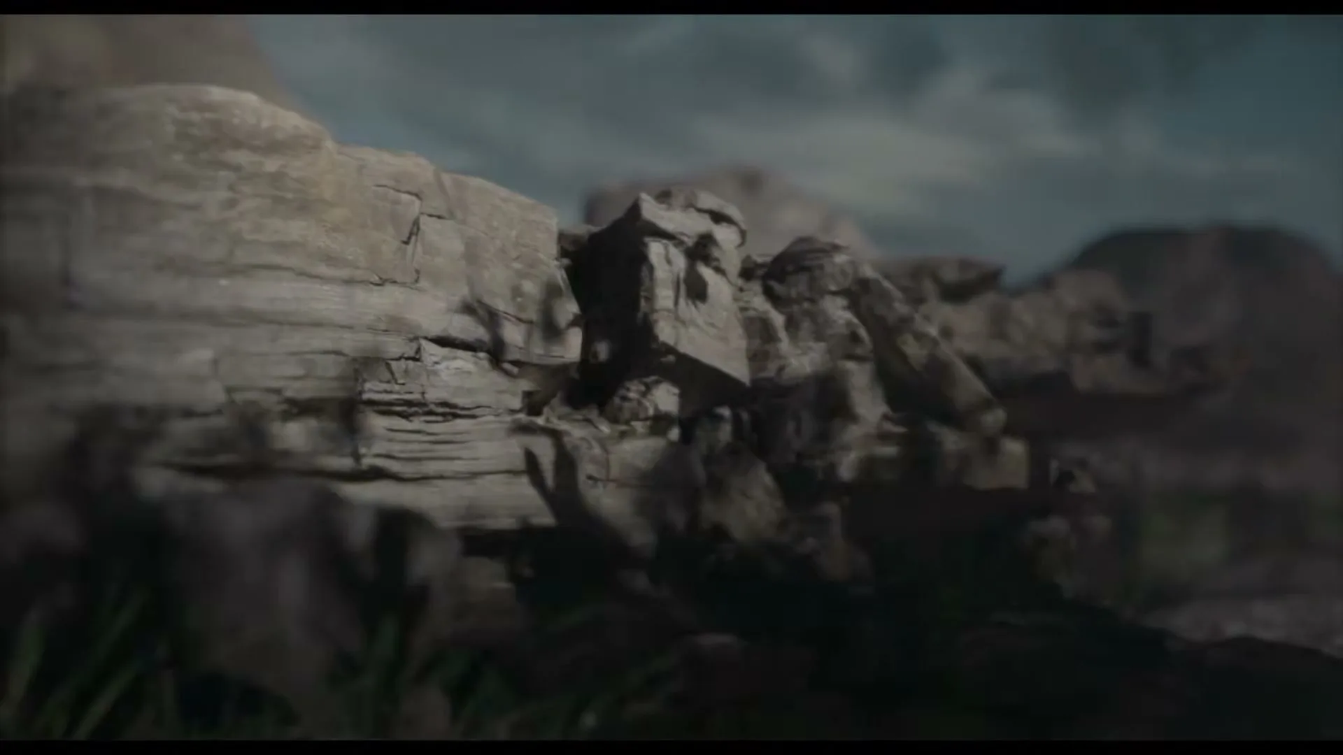 A wide shot of a rocky landscape with a cloudy sky, as the camera slowly pans right, revealing more of the rugged terrain.