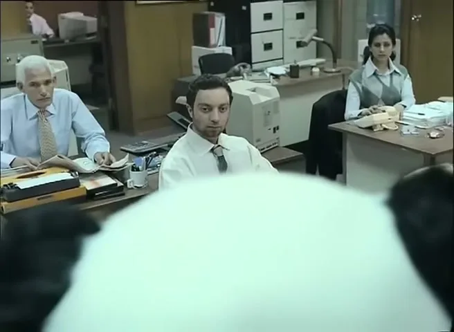 Three office workers look up from their desks with fearful expressions at a giant panda that is not visible in the shot.