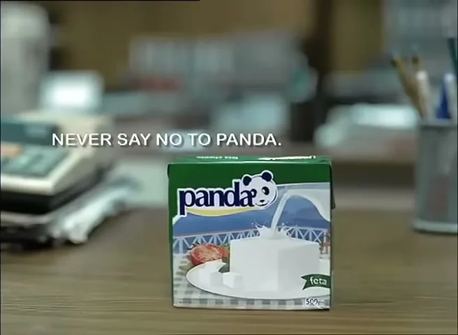 A furry black hand slams a small carton of Panda feta cheese onto a wooden desk, with the text "NEVER SAY NO TO PANDA." appearing on screen.