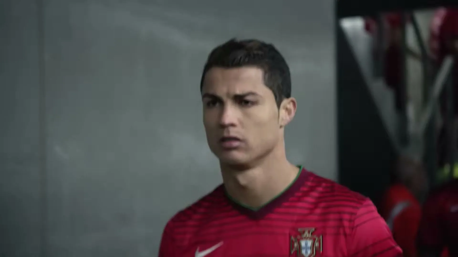 Cristiano Ronaldo, a male soccer player in a red jersey, walks through a stadium tunnel with a serious expression.