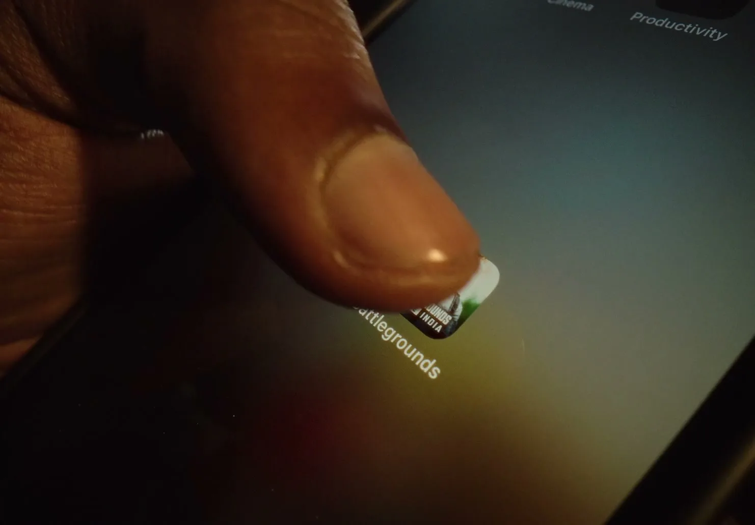 A person's finger taps on the "Battlegrounds" app icon on a smartphone screen, initiating the game.