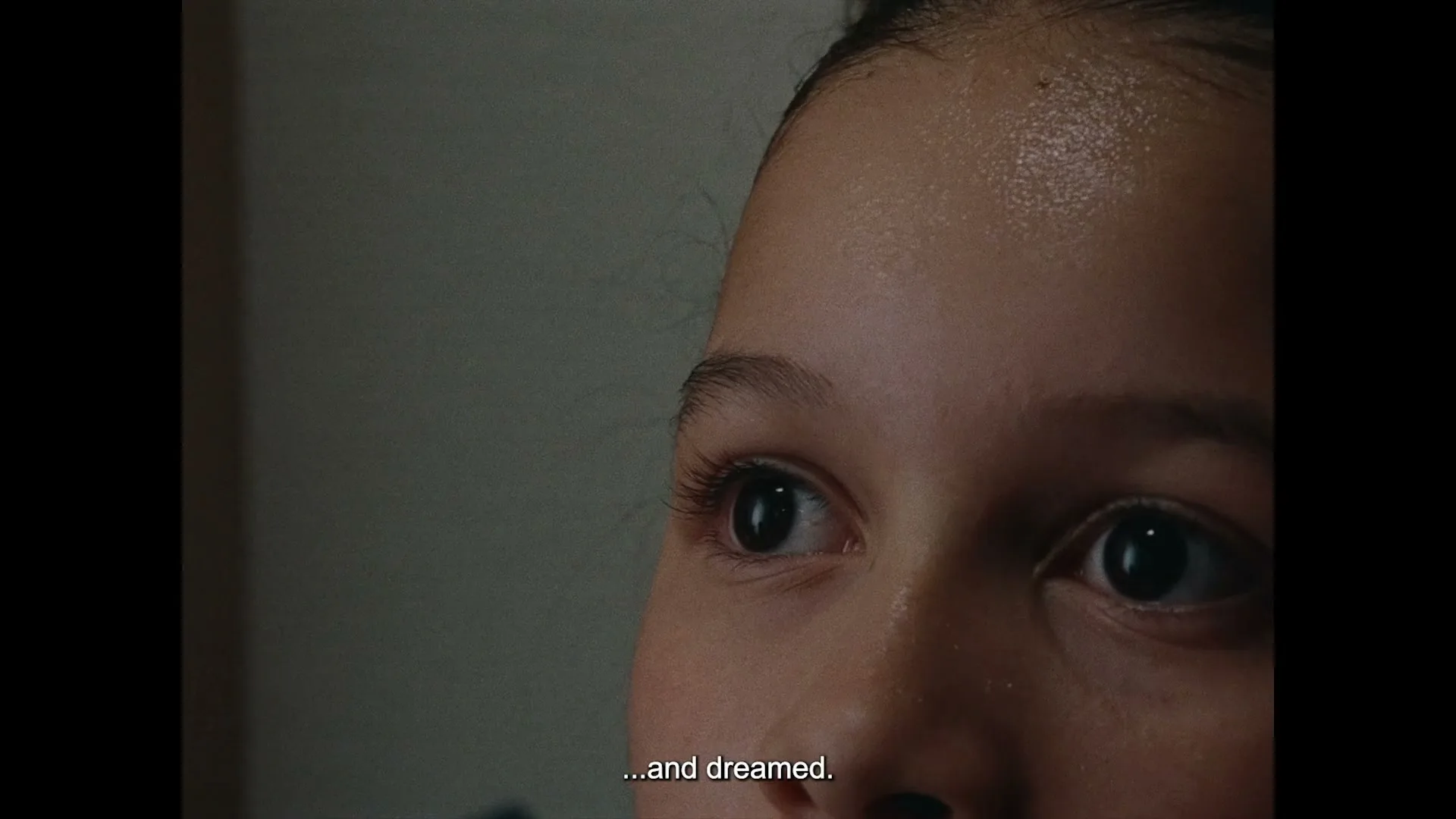A young girl's eyes are shown in a close-up, looking upwards with a thoughtful expression, in an interior setting.
