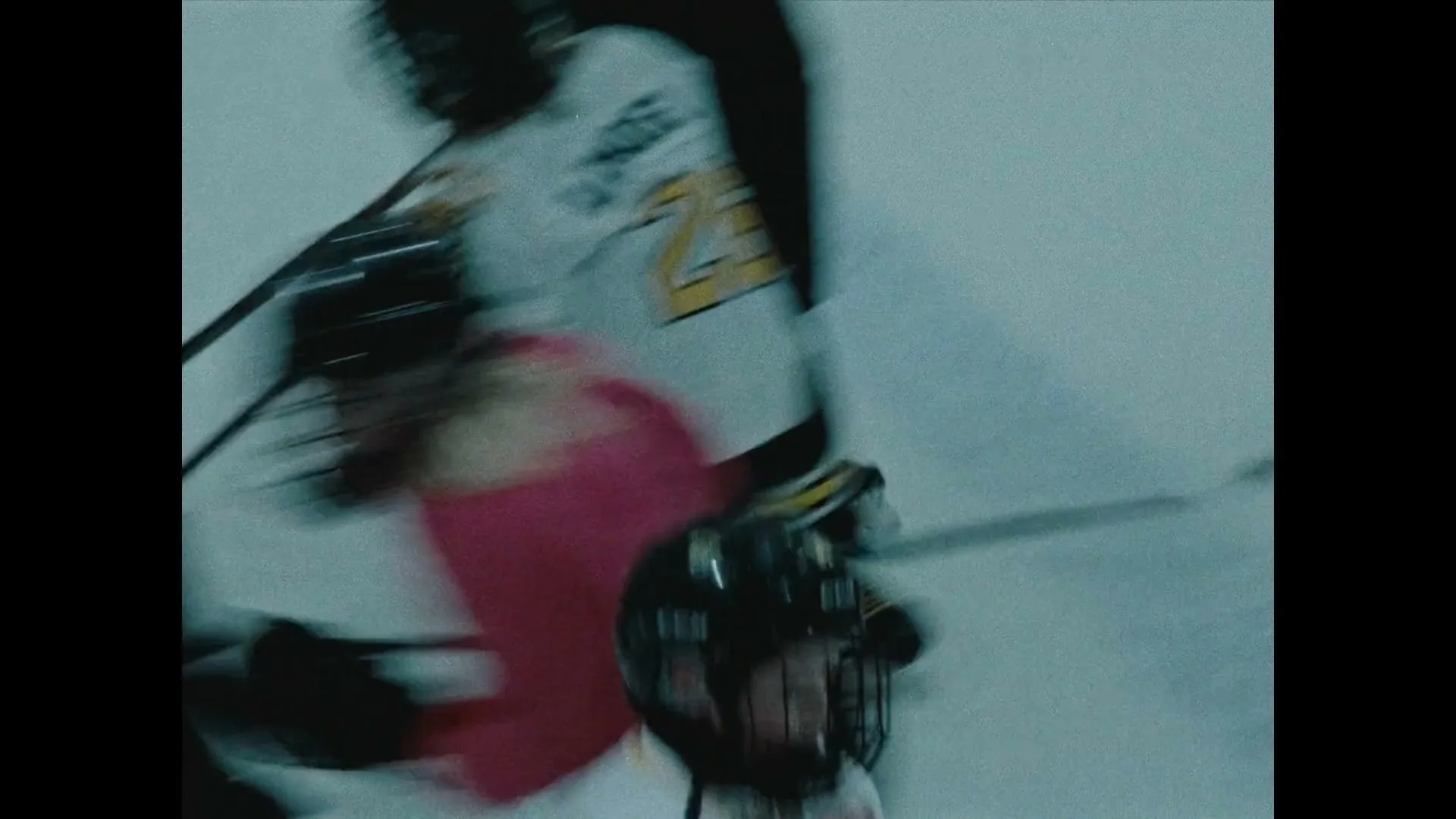 Two ice hockey players, one in a white jersey with a tiger logo and the other in a pink top, skate rapidly on an ice rink during a game.