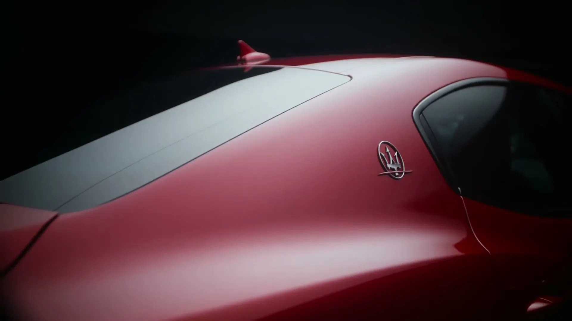 A close-up shot of the sleek, red Maserati car, highlighting its elegant design and the iconic trident logo on the side.