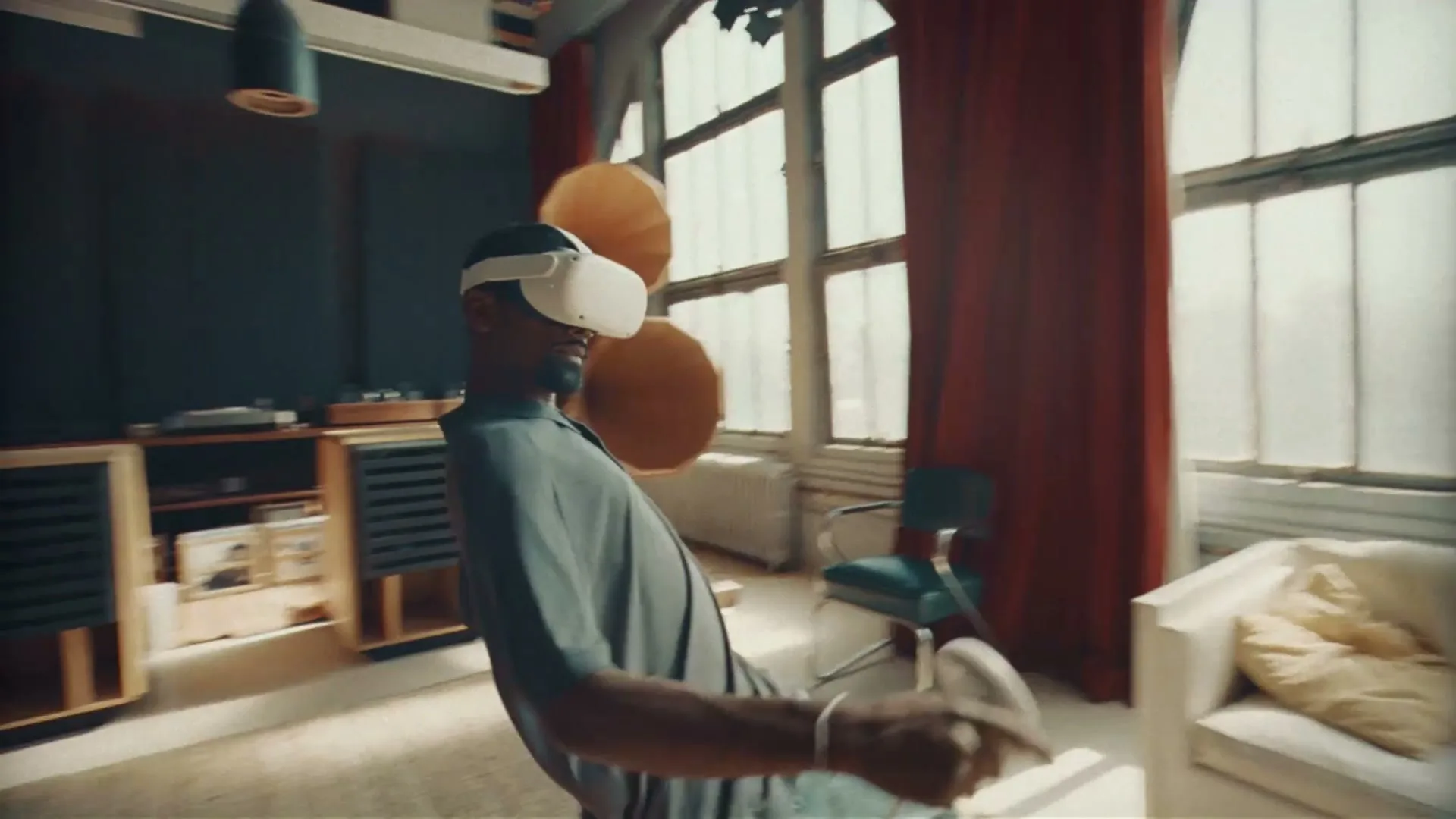 A man wearing a VR headset and casual clothes leans back, holding a controller, in a sunlit, vintage-style living room with large windows.