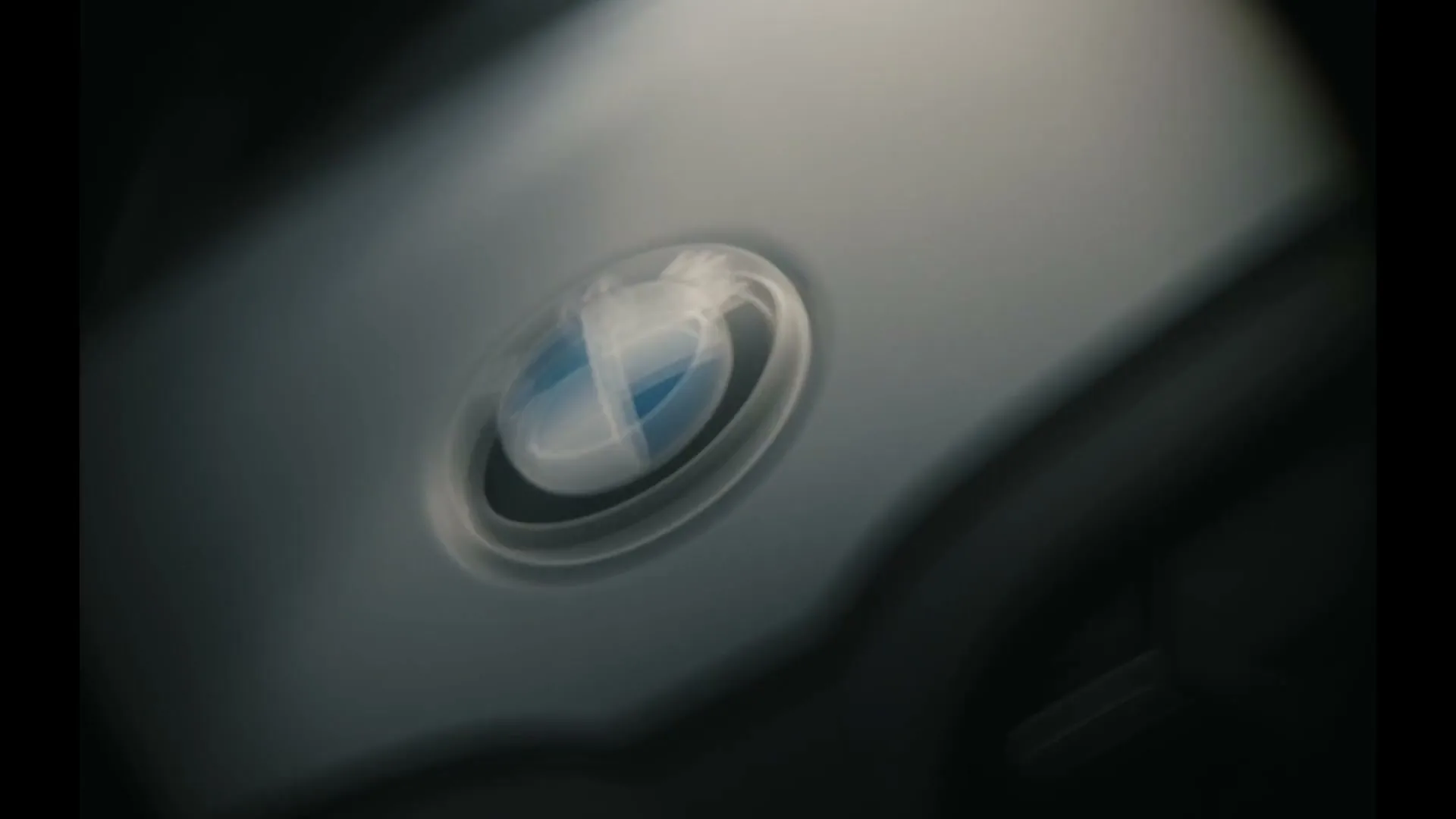 The BMW logo, initially blurred, comes into sharp focus on a dark gray car body, highlighting its iconic design.