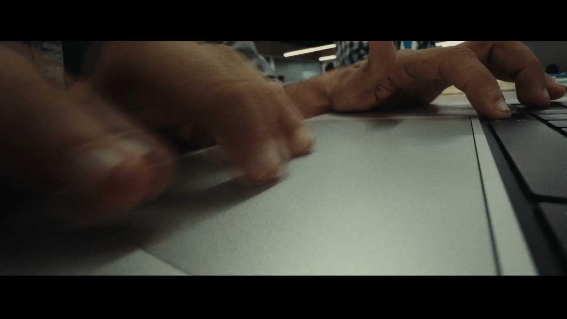 A person's hands are seen typing on a laptop keyboard and using the trackpad in a close-up shot.