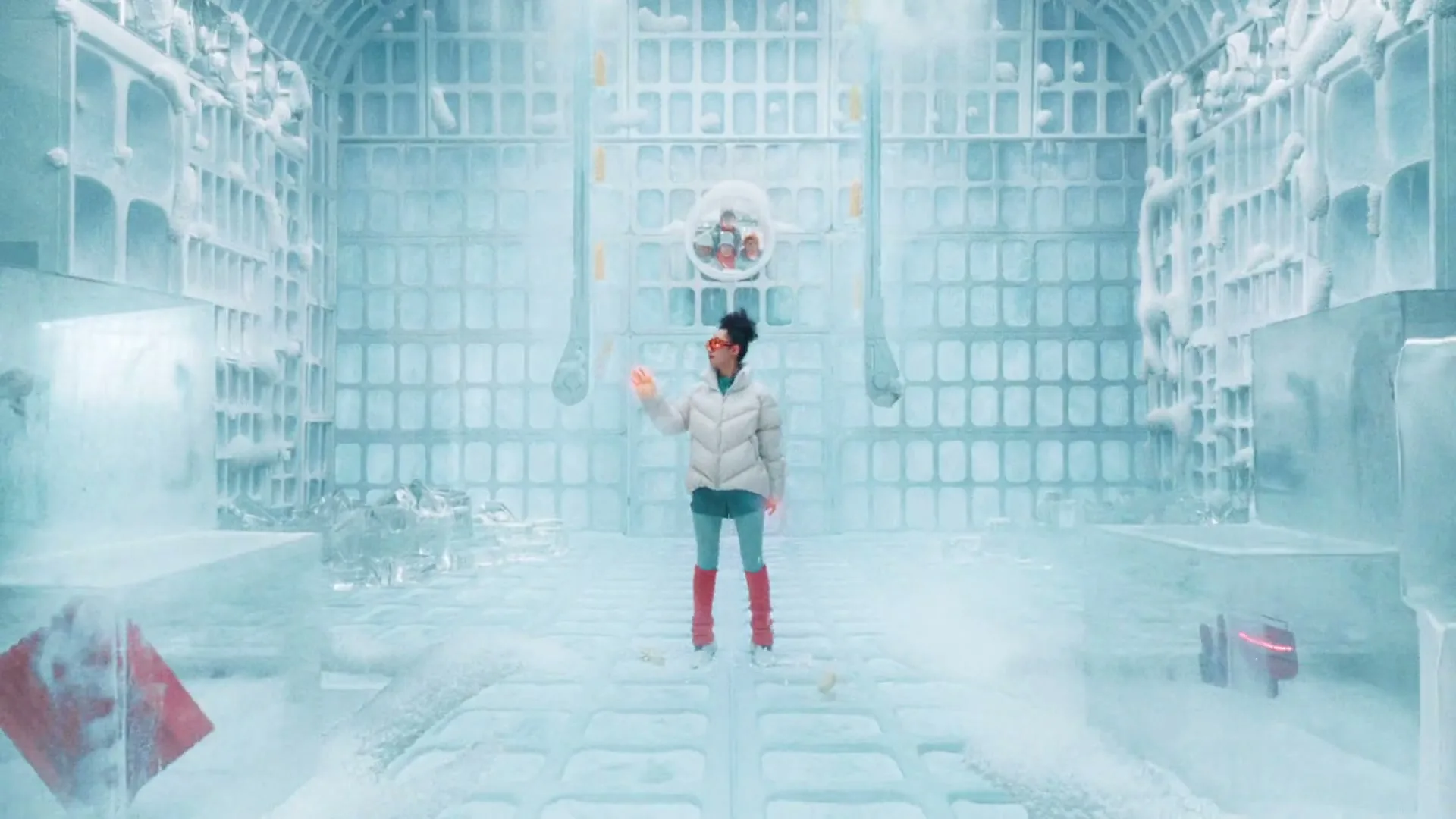 A young woman in a white puffer jacket and red boots stands in a futuristic, icy chamber, looking around with curiosity.