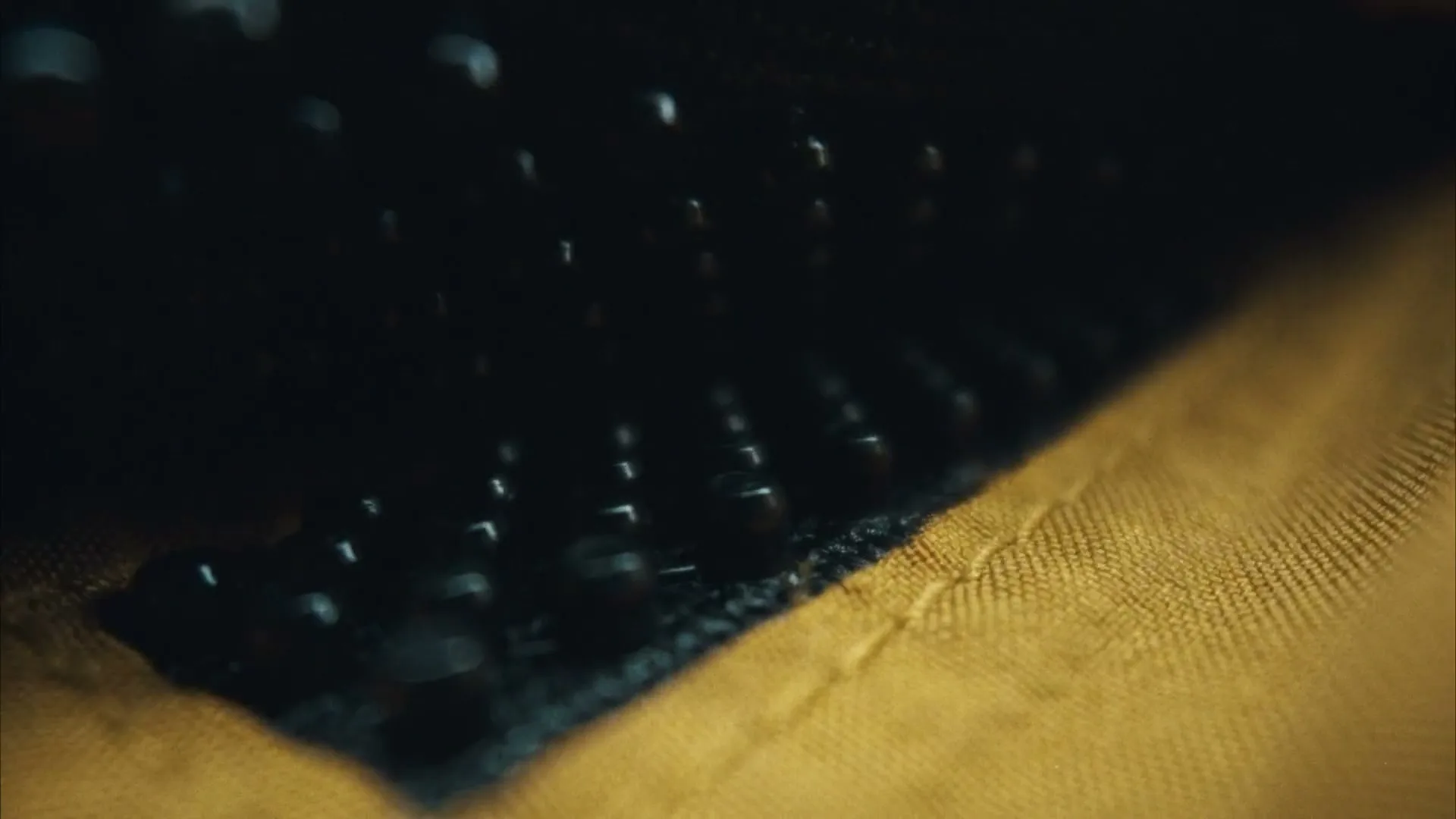 A close-up shot of a black zipper on a yellow fabric, with the zipper teeth slowly closing as the camera moves.