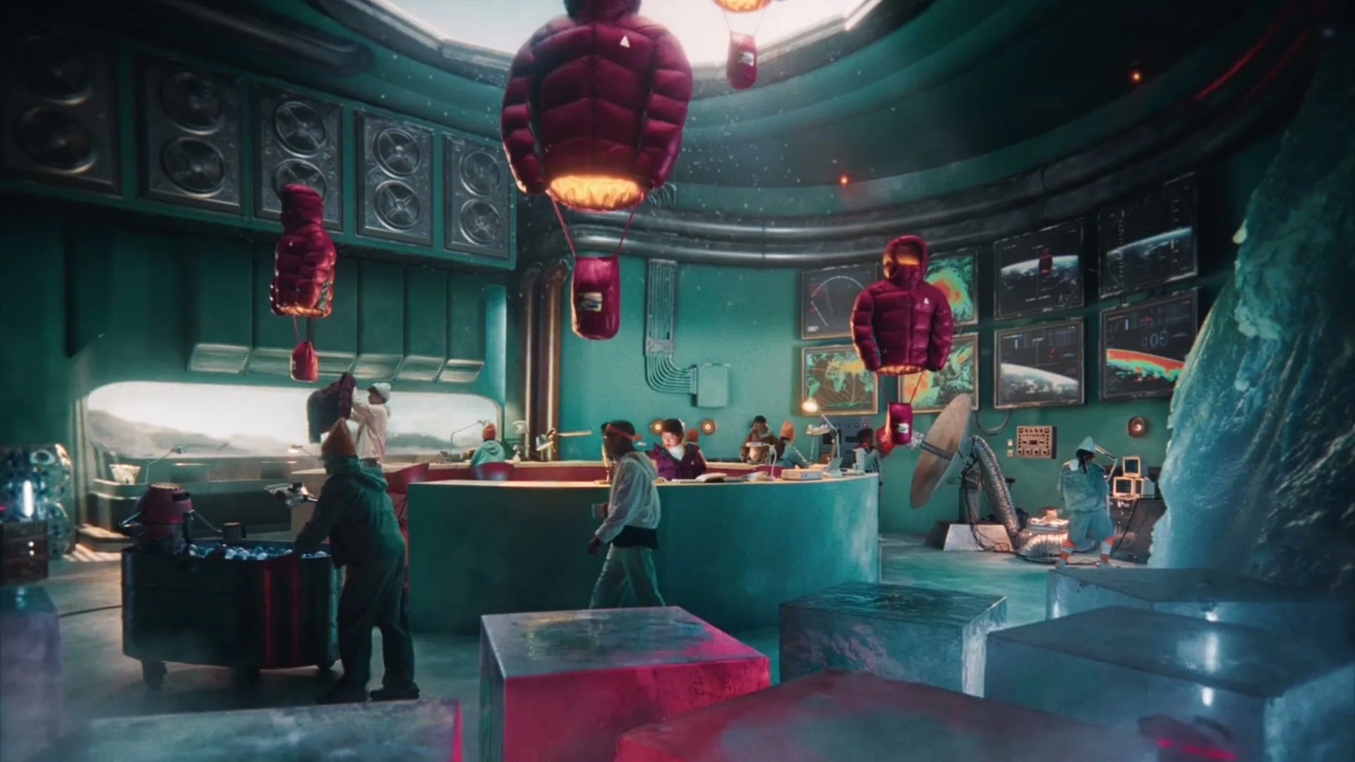 A wide shot shows a futuristic, circular control room with several people working, while red puffer jackets float in the air.