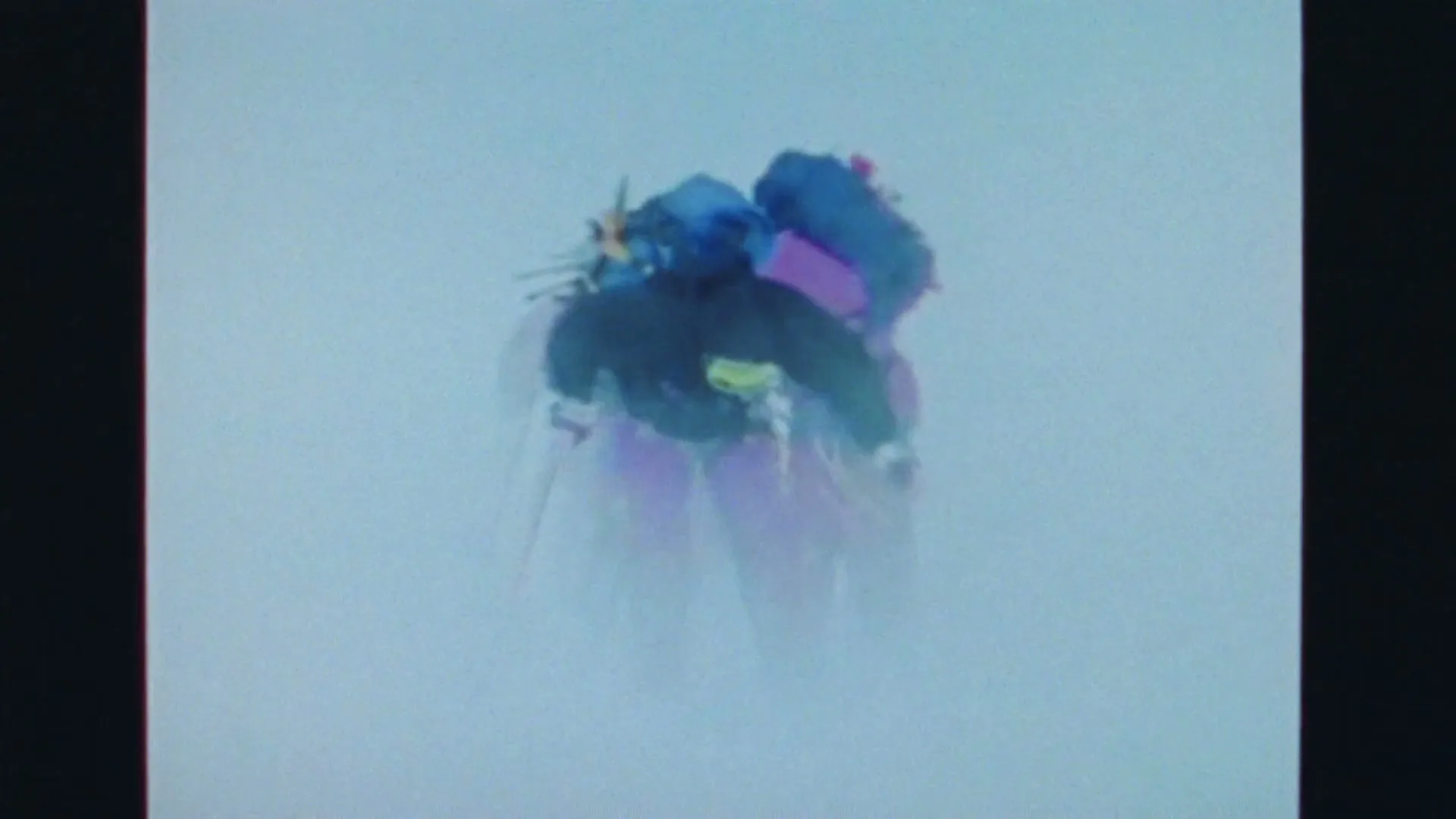 Two people in winter gear and backpacks hike through a snowy, foggy mountain landscape, seen from above.