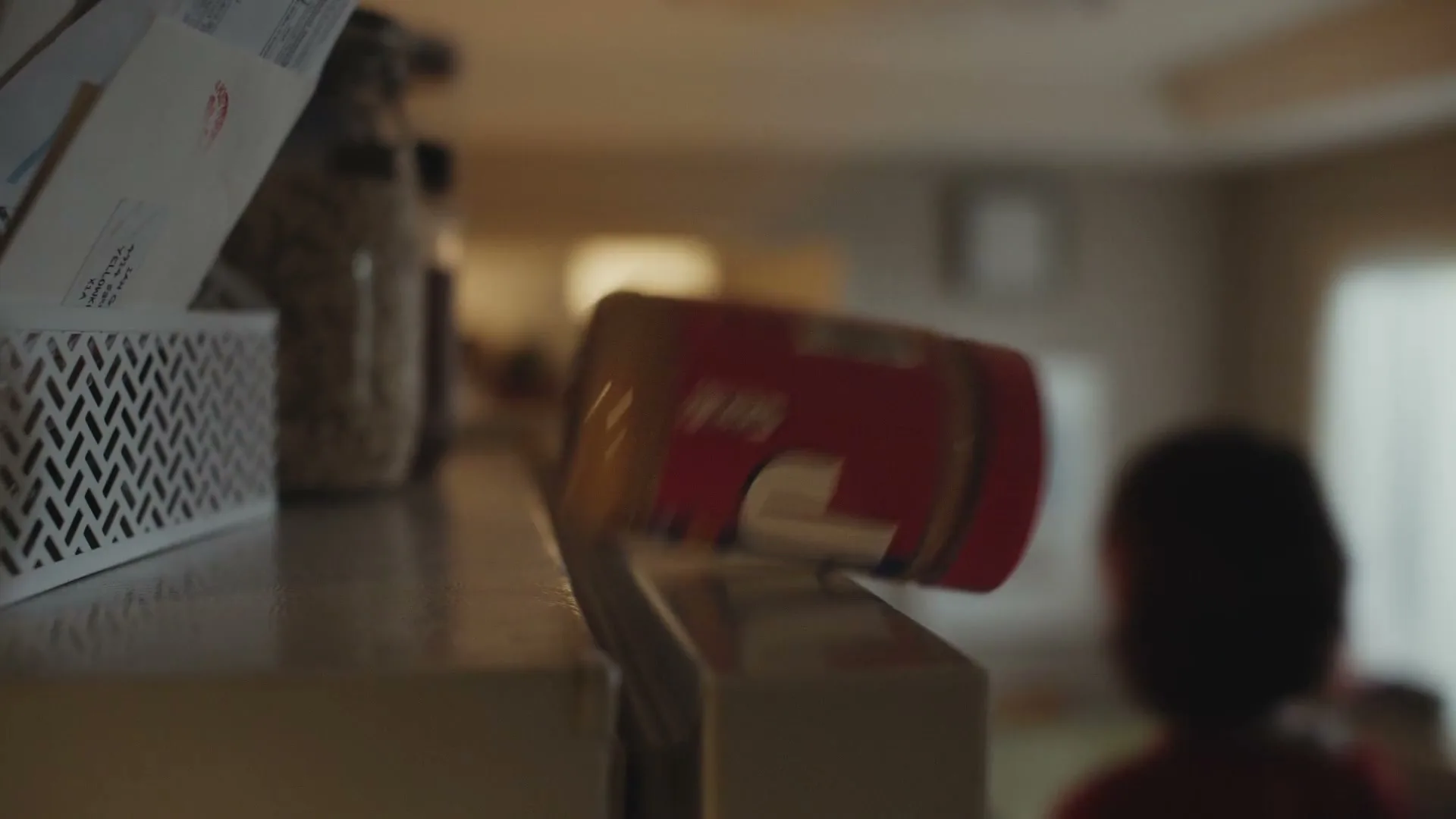 A jar of Jif peanut butter falls off a counter in a home kitchen, with a blurred child in the background.
