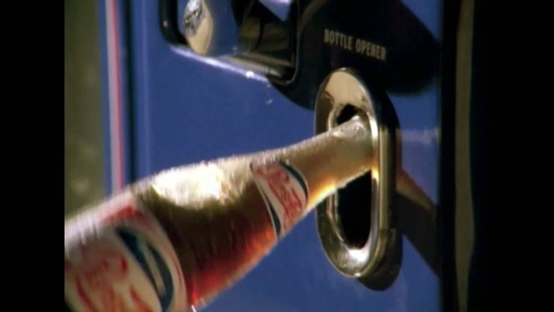A close-up shot shows a bottle of Pepsi being opened by a bottle opener on a blue vending machine, with foam spilling out.