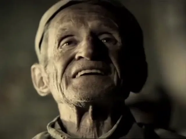 A prison guard in a tan uniform pulls a rat out of a loaf of bread, then an old male prisoner looks up with a pained expression in a dark prison.