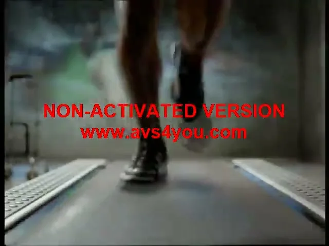 A male athlete with dark skin and a mustache runs on a treadmill in a gym, wearing a tank top and shorts.
