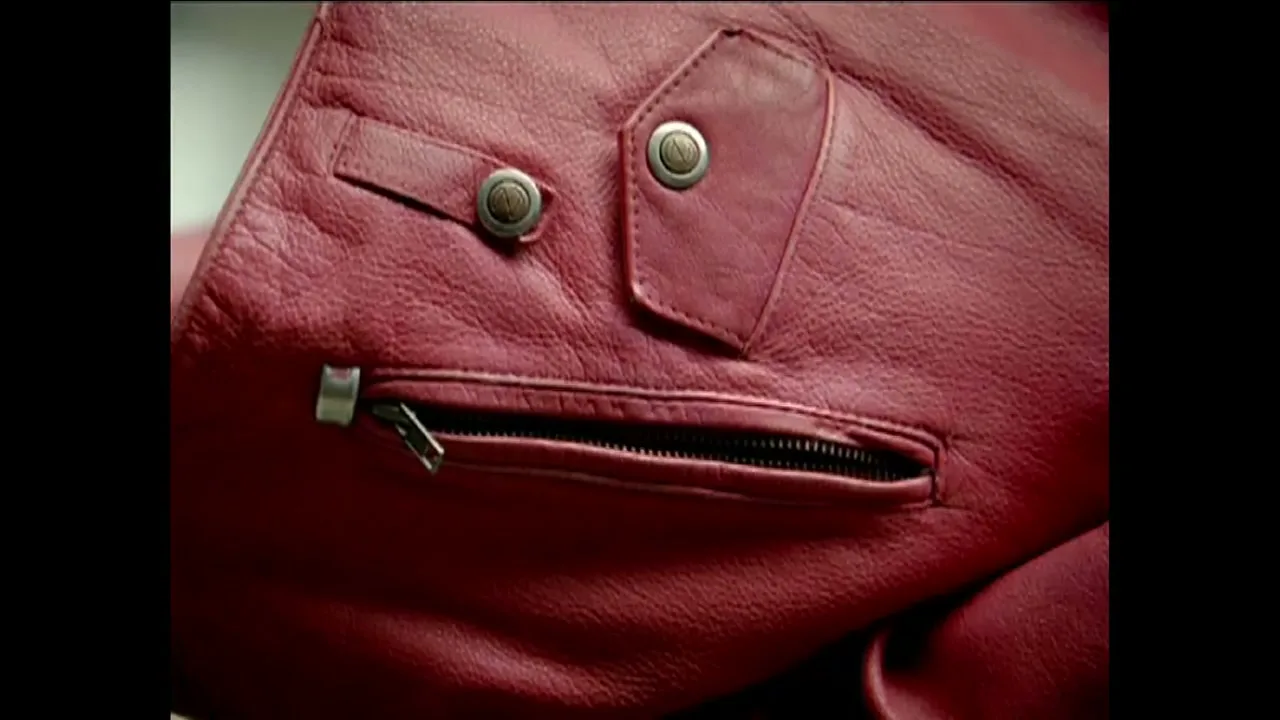 A red leather jacket with buttons and a zipper forms a face, creating a playful and anthropomorphic image.