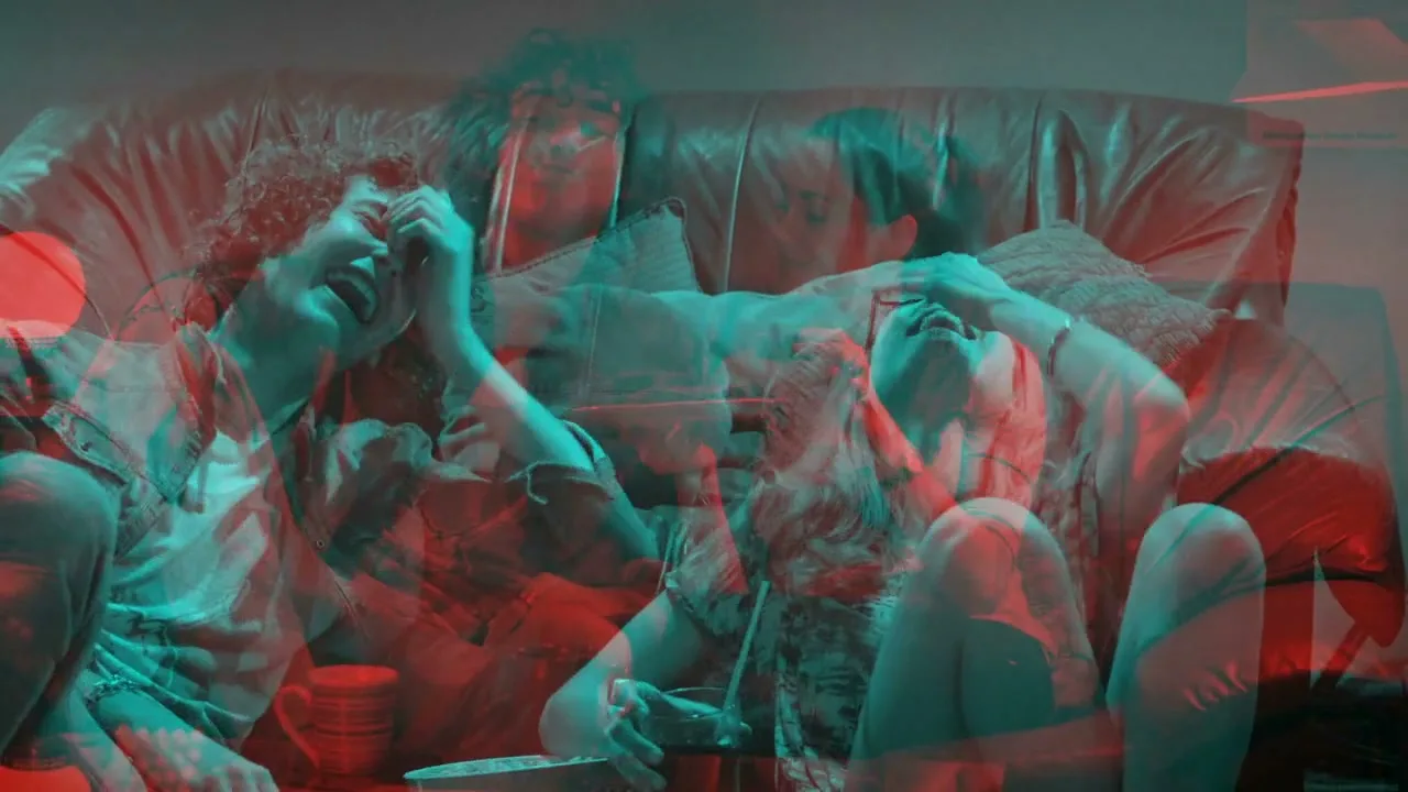 Three young adults, two men and one woman, laugh hysterically on a brown leather couch in a living room, with a red and cyan anaglyph 3D effect.