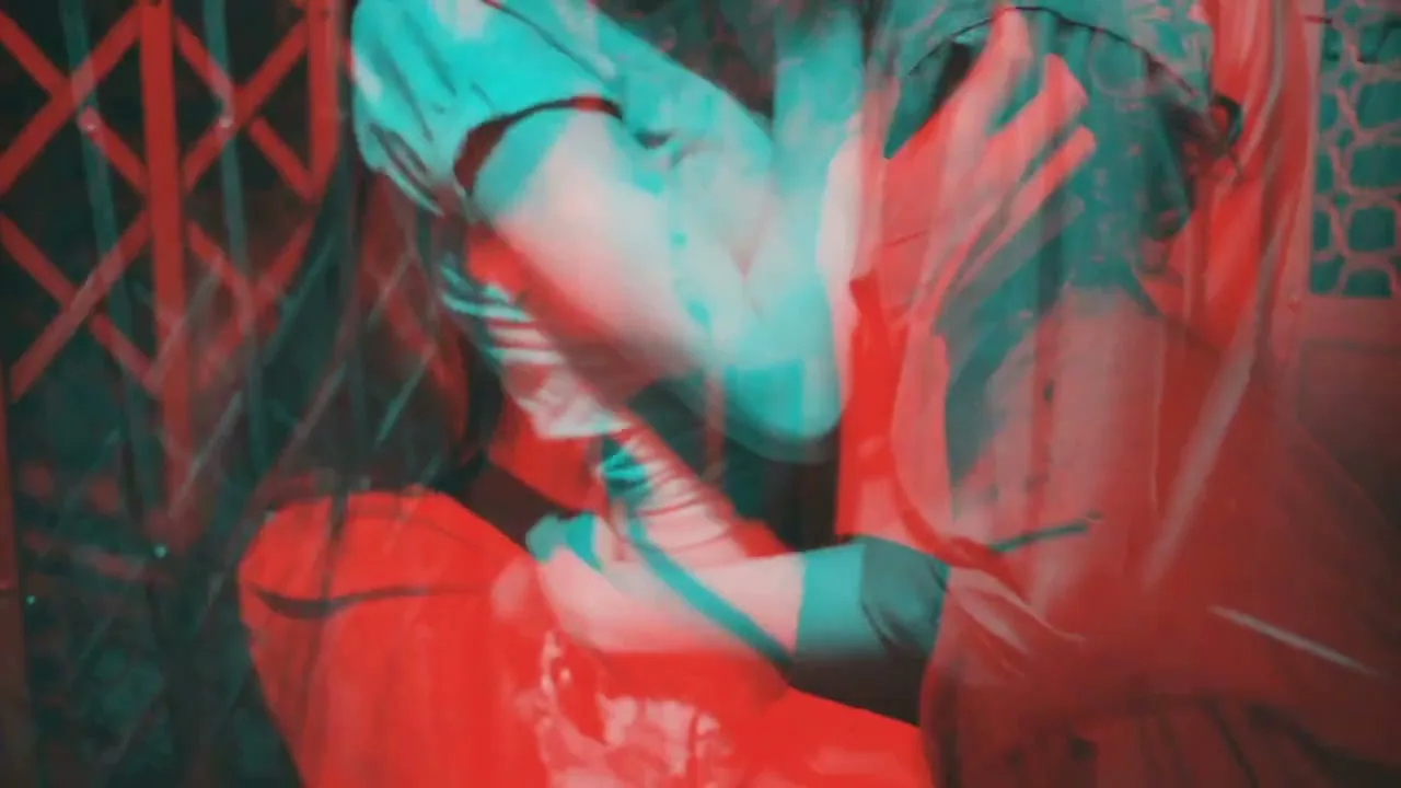 A man and woman are seen in a tight embrace, with a red and cyan anaglyph 3D effect applied to the footage, creating a distorted, dreamlike appearance.