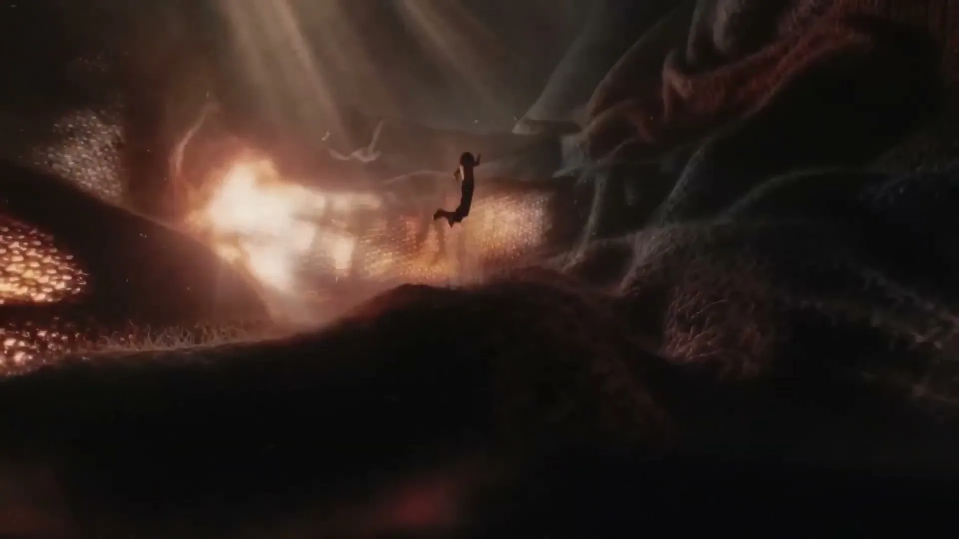 A tiny silhouetted figure floats in a vast, dark, organic landscape with glowing orange light emanating from the left.