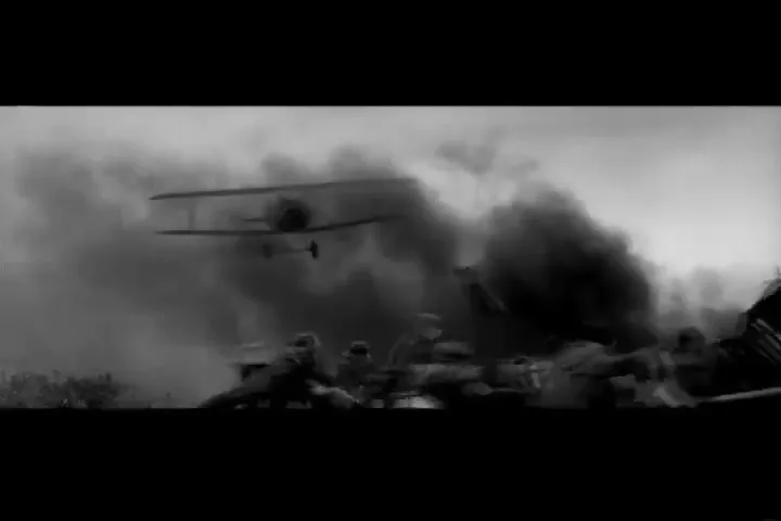 Soldiers in military uniforms are seen on a battlefield as a biplane flies low over them, surrounded by smoke and debris.
