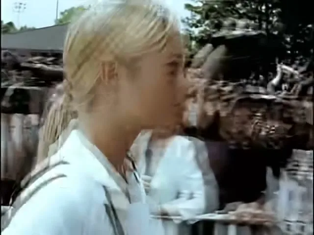 Maria Sharapova, a blonde female tennis player, walks through a crowd of fans and then down a hallway, looking determined.