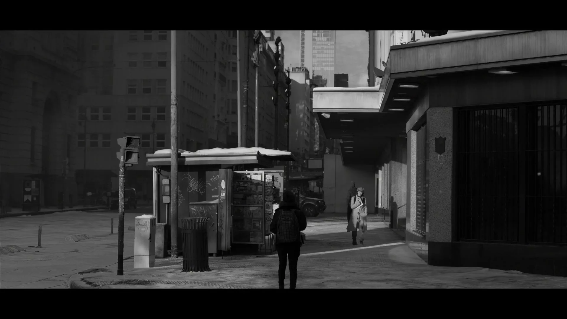 A woman in a dark jacket walks away from the camera on a snowy city street, while another woman in a light coat walks towards her.